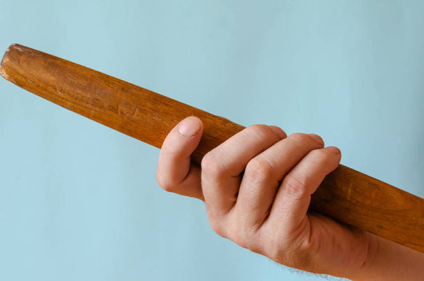 Hand holds a wooden rolling pin. The right hand of a person with a device for rolling out the dough. Caucasian man 43-45 years old. Kitchenware - Foto, Bild