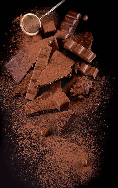 Broken chocolate pieces and cocoa powder on wooden background - Valokuva, kuva