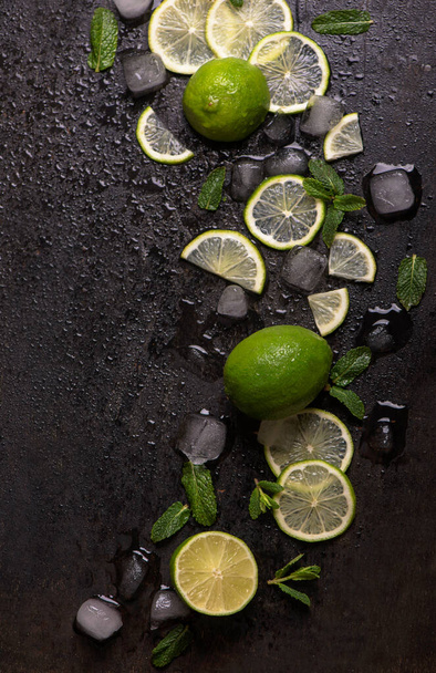 Fresh mint, lime and ice on a black background. Ingredient for mahito. Top view - Foto, immagini