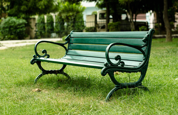 Rahatlamak için parka yerleştirilmiş yeşil bir bank. - Fotoğraf, Görsel