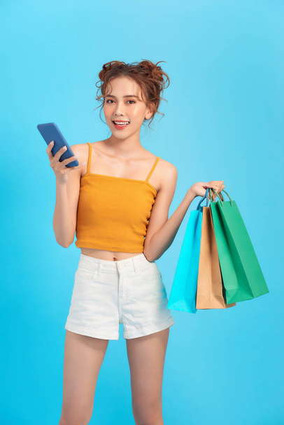 Felice shopper posa in possesso di uno smartphone e borse della spesa - Foto, immagini