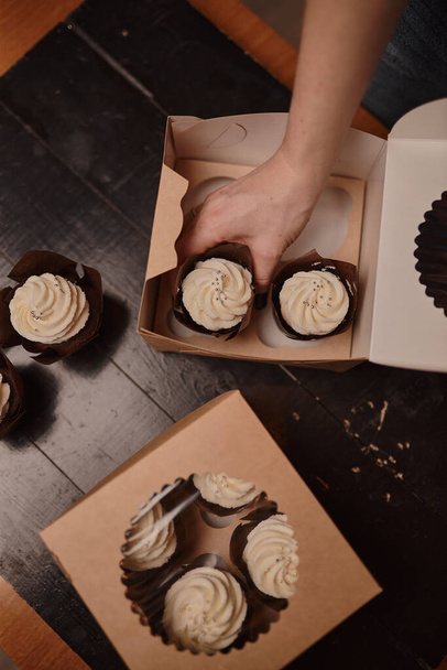 Packaging of delicious homemade muffins with whipped cream in a cardboard box. - Fotoğraf, Görsel