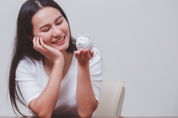 Hucha en la mano de la mujer sonriente, ahorrar dinero y gestión concepto financiero
. - Foto, Imagen
