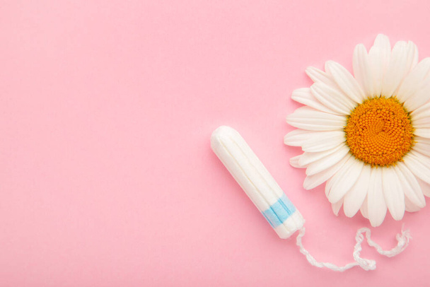 Medicinal chamomile flower and menstrual sanitary tampon. Medical conceptual photo on pink - Photo, Image