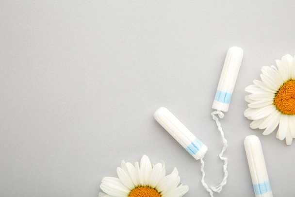 Medicinal chamomile flower and menstrual sanitary tampon. Medical conceptual photo on grey. - Foto, immagini