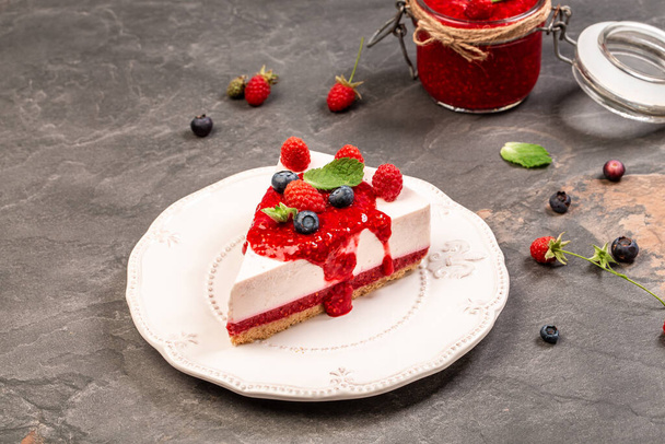 Plate with piece of tasty cheesecake on table. Homemade cheesecake with raspberry jelly. - Фото, изображение