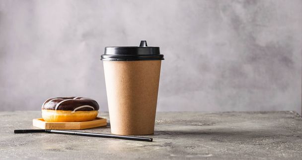 Copo de papel com bebida de café ou donut de chá em cobertura de chocolate em um fundo cinza. Conceito de comida e bebida Zero West
. - Foto, Imagem