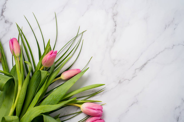 Closeup of beautiful red tulips with green herbs on a marble background on a table with copy space - Fotografie, Obrázek