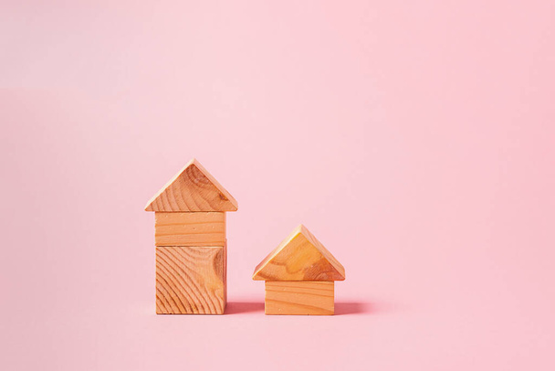 Childrens wooden toys on a pink background concept zero west. Small houses the designer from developing color cubes - Fotografie, Obrázek