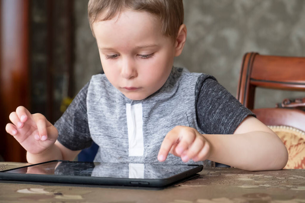 Маленький хлопчик грає в ігри на планшеті на столі. крупним планом
 - Фото, зображення