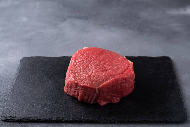 Siyah taş tahtada çiğ biftek. Domuz filetosu. Metin için boşluk - Fotoğraf, Görsel