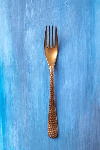 Antigue fork on blue background. Top view - Foto, afbeelding