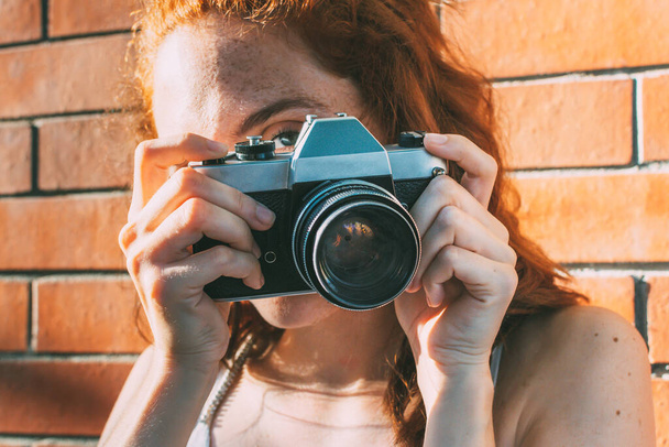 young woman holds an analog camera and looks through the viewfinder - Foto, Bild