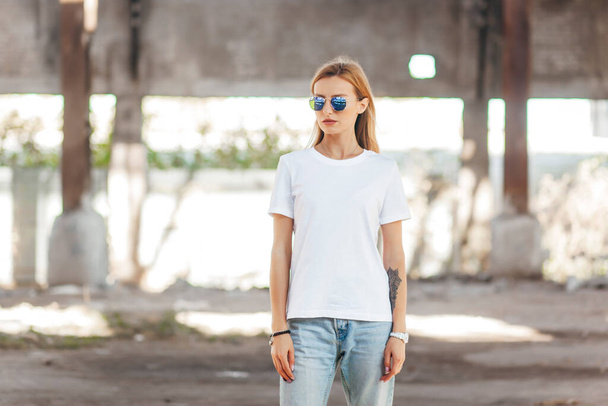 Ragazza che indossa t-shirt e occhiali in posa contro strada, stile di abbigliamento urbano. Foto di strada - Foto, immagini