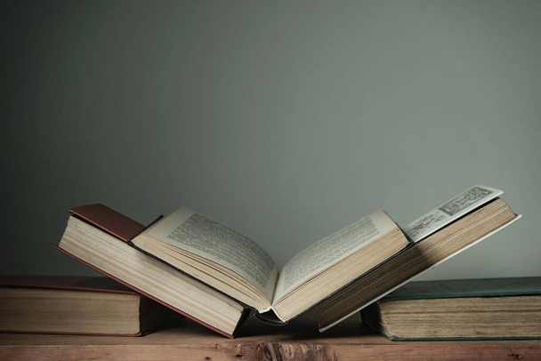 Bellissimi libri aperti su un vecchio tavolo di legno rosso e sfondo bianco della parete. - Foto, immagini