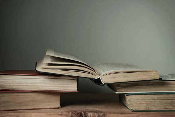 Gyönyörű nyitott könyvek egy régi piros fa asztal és fehér fal háttér. - Fotó, kép