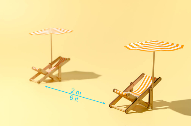 Twee ligstoelen met parasols op het strand na een coronavirus pandemie. - Foto, afbeelding