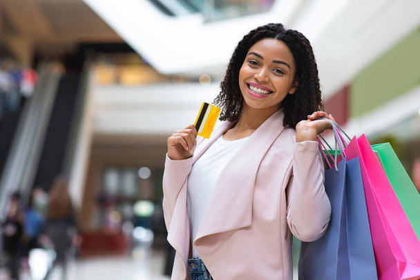 Простые платежи. Черная женщина с кредитной картой и сумки в торговом центре
 - Фото, изображение