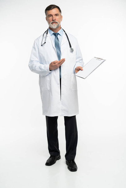 full body picture of a mature doctor holding a notepad, on white background. - Foto, afbeelding