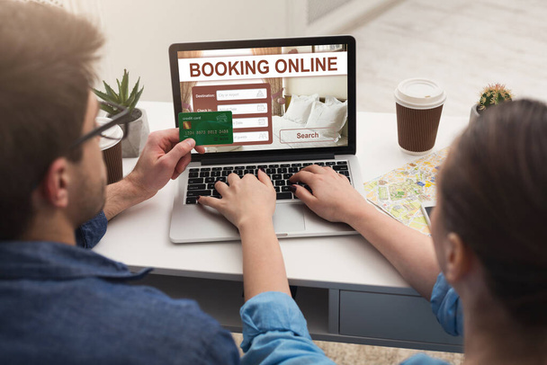 Couple faisant réservation d'hôtel en ligne, en utilisant un ordinateur portable - Photo, image