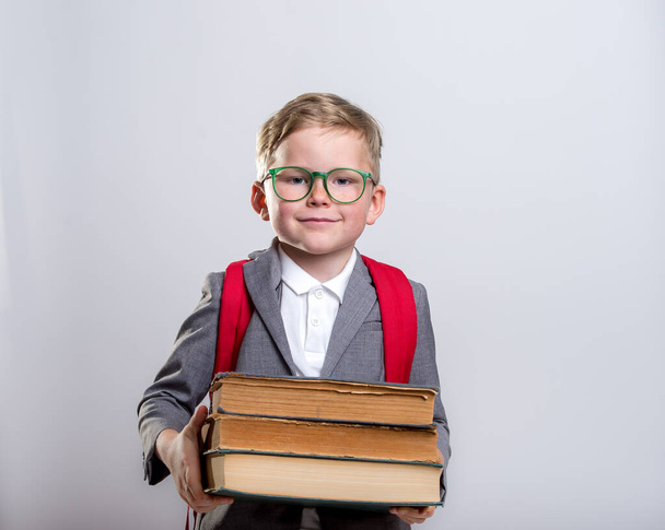 Happy little boy with books isolated on white background. Back to school. Smark pupil in glasses. - Foto, afbeelding