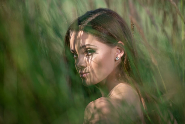 Beautiful young woman posing in a grass field - Фото, зображення