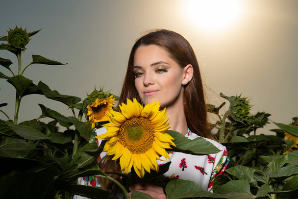 Beautiful young girl posing at sunset in a sunflower field - Photo, Image