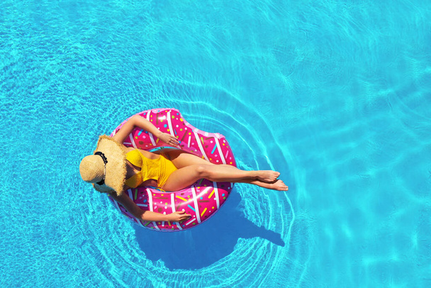 Young woman with inflatable ring in swimming pool, top view - Fotoğraf, Görsel