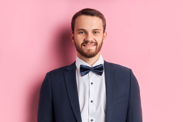 Mladý pohledný muž v obleku a kravatě izolované přes růžové pozadí - Fotografie, Obrázek
