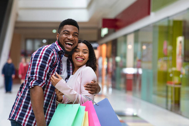 Щасливі покупці. Весела африканська пара позує в універмазі після успішних покупок
 - Фото, зображення