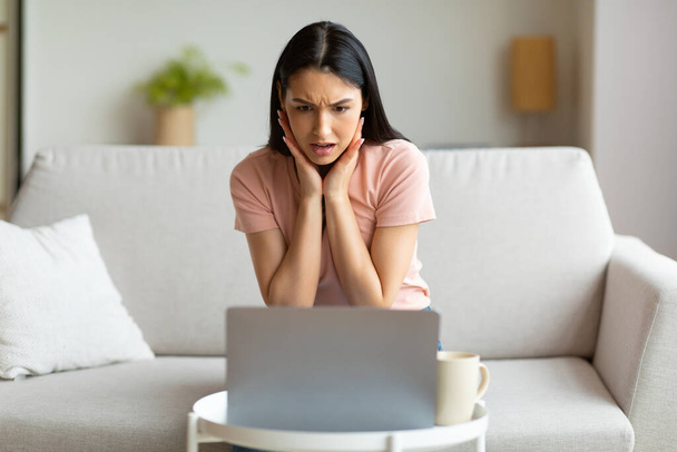Femme choquée à l'ordinateur portable ayant une mauvaise connexion Internet à la maison - Photo, image