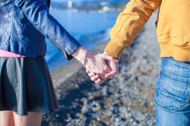 Вид сзади на мужчину и женщину, держащихся за руки на морском фоне
 - Фото, изображение