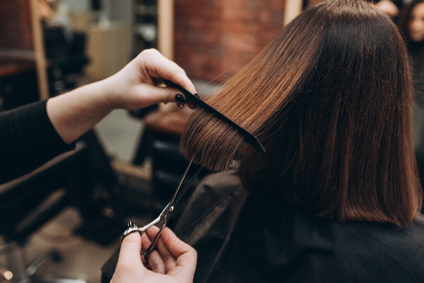 Maestro peluquero corta el pelo de una chica con tijeras
 - Foto, imagen