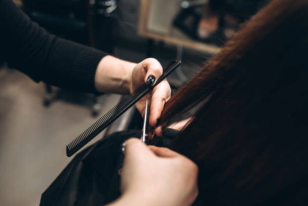 A mester fodrász ollóval vágja egy lány haját. - Fotó, kép