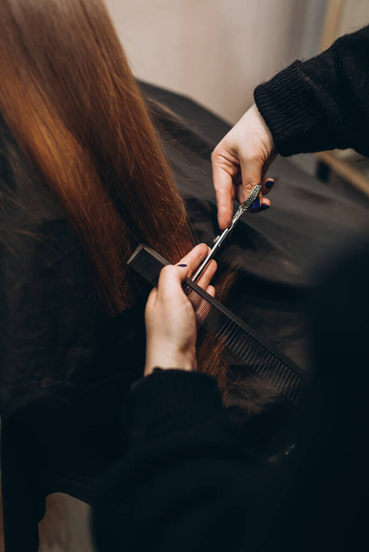 Maestro peluquero corta el pelo de una chica con tijeras
 - Foto, Imagen