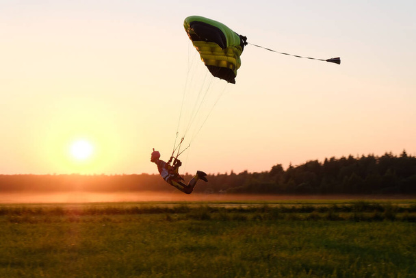 Прыжки с парашютом Скайдайвер приземляется. Фон заката
. - Фото, изображение