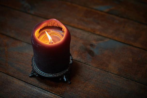 Vela grande sobre mesa de madera. Vela ardiente en un candelero, estilo gótico vintage, espacio para copiar. Diseño para rituales mágicos y predicciones - Foto, Imagen