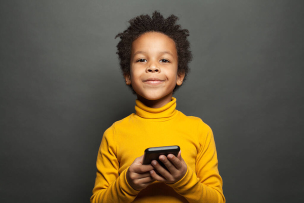 Feliz sorrindo menino criança negra com smartphone
 - Foto, Imagem