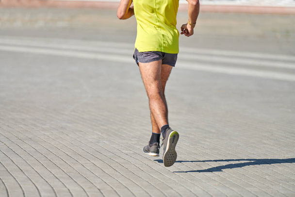 Běžící muž. Atletický muž běhá ve sportovním oblečení na městské silnici. Zdravý životní styl, sportovní koníček. Pouliční cvičení, sprintování venku - Fotografie, Obrázek