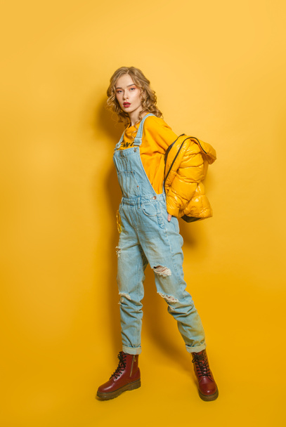 Femme de mode en duvet et combinaison en denim sur fond jaune vif - Photo, image