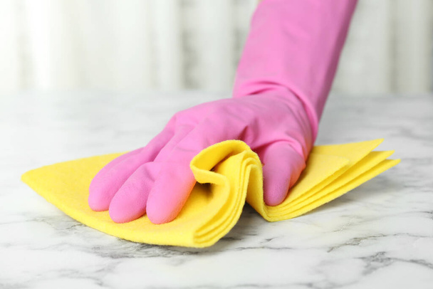 Woman in gloves wiping white marble table with rag indoors, closeup - Photo, Image