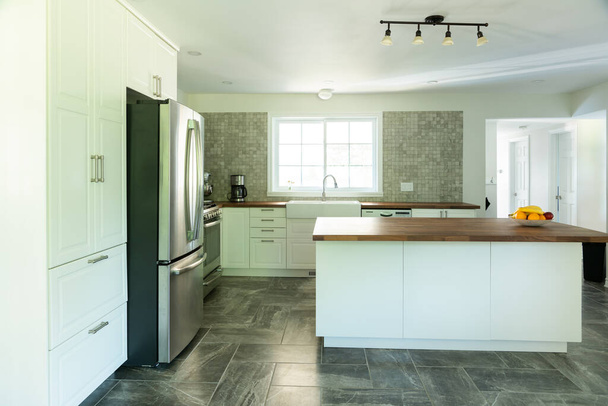 Nueva cocina gris y blanca con electrodomésticos y encimera de madera
 - Foto, imagen