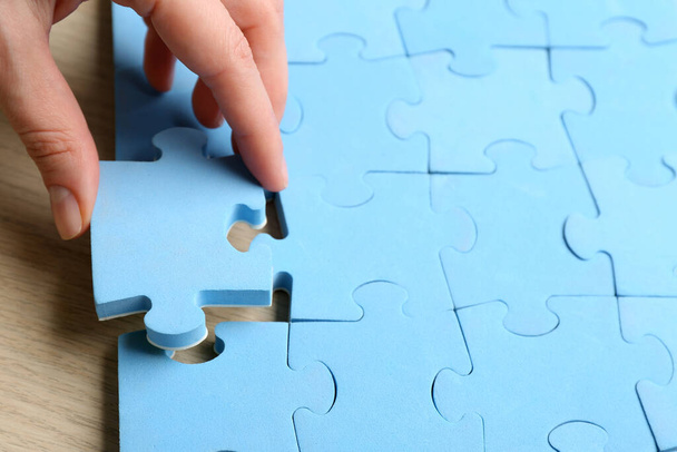 Woman putting light blue puzzle piece, closeup with space for text. Career promotion concept - Фото, зображення