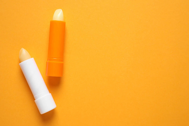 Hygienic lipsticks on orange background, flat lay. Space for text - Photo, Image