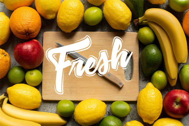 κορυφαία άποψη των νόστιμων πολύχρωμων φρούτων και ξύλινη επιφάνεια κοπής με μαχαίρι, φρέσκια απεικόνιση - Φωτογραφία, εικόνα