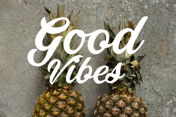 top view of ripe pineapples on grey concrete surface, good vibes illustration - Foto, imagen