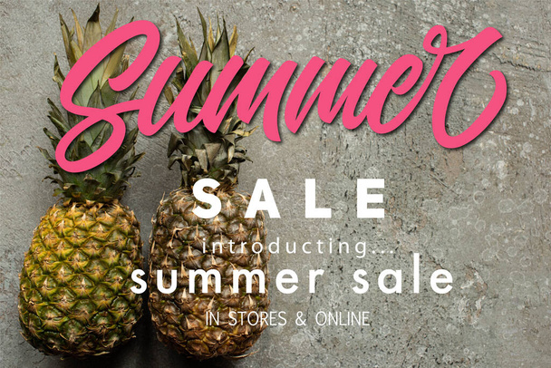 top view of ripe pineapples on grey concrete surface with summer sale illustration - Foto, Imagen