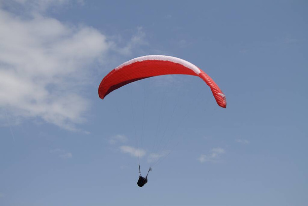 A person paragliding above a beautiful mountainous landscape - Fotó, kép