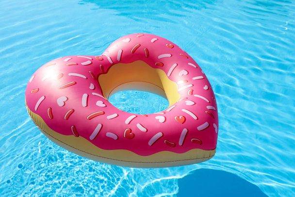 Herzförmiger aufblasbarer Ring, der im Schwimmbad schwimmt. Sommerferien - Foto, Bild