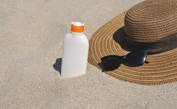 Botella con crema de protección solar sobre textura de arena. - Foto, imagen